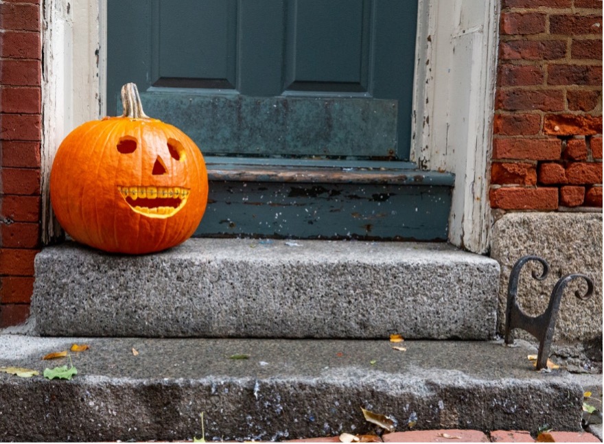 Jack o lantern with braces sitting on front door step