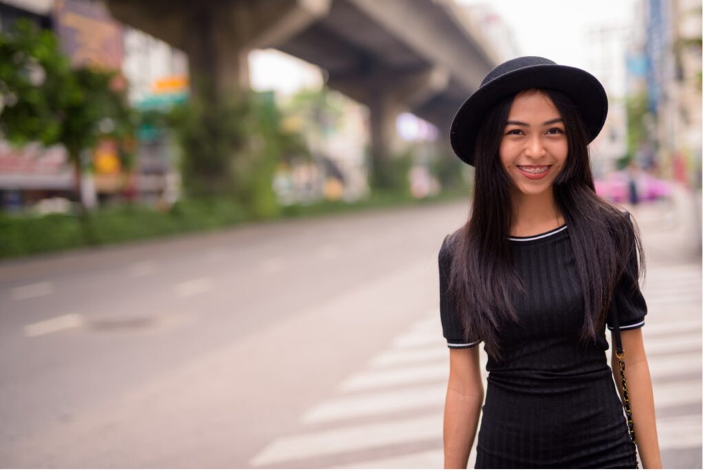 A person in a black hat with braces smiling, clothing that complements your braces