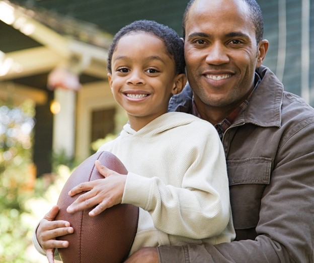 A person holding a child and a football, Score Big with Children's Orthodontic Care!