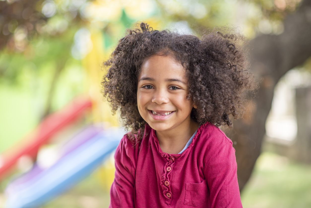 Celebrating Smiles at 7 Day with Early Orthodontic Care in Murray, Utah, A child with frilly hair smiling
