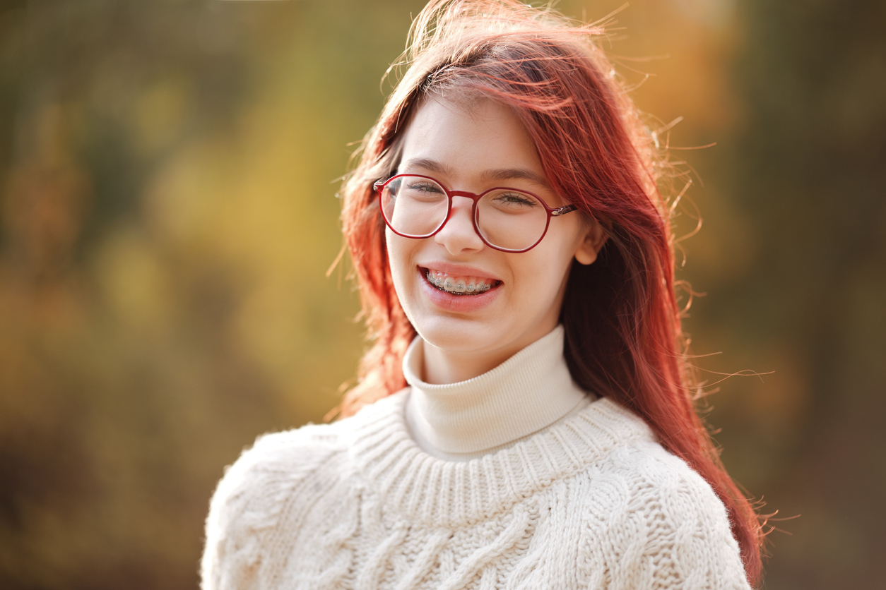 Why Starting Orthodontic Treatment This Fall Is Something to Smile About, Beautiful smiling teenage girl with long red hair. Autumn colors.